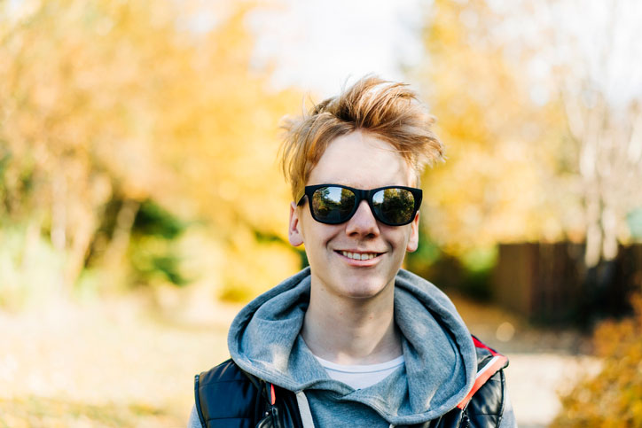 smiling teenage boy wearing sunglasses at park